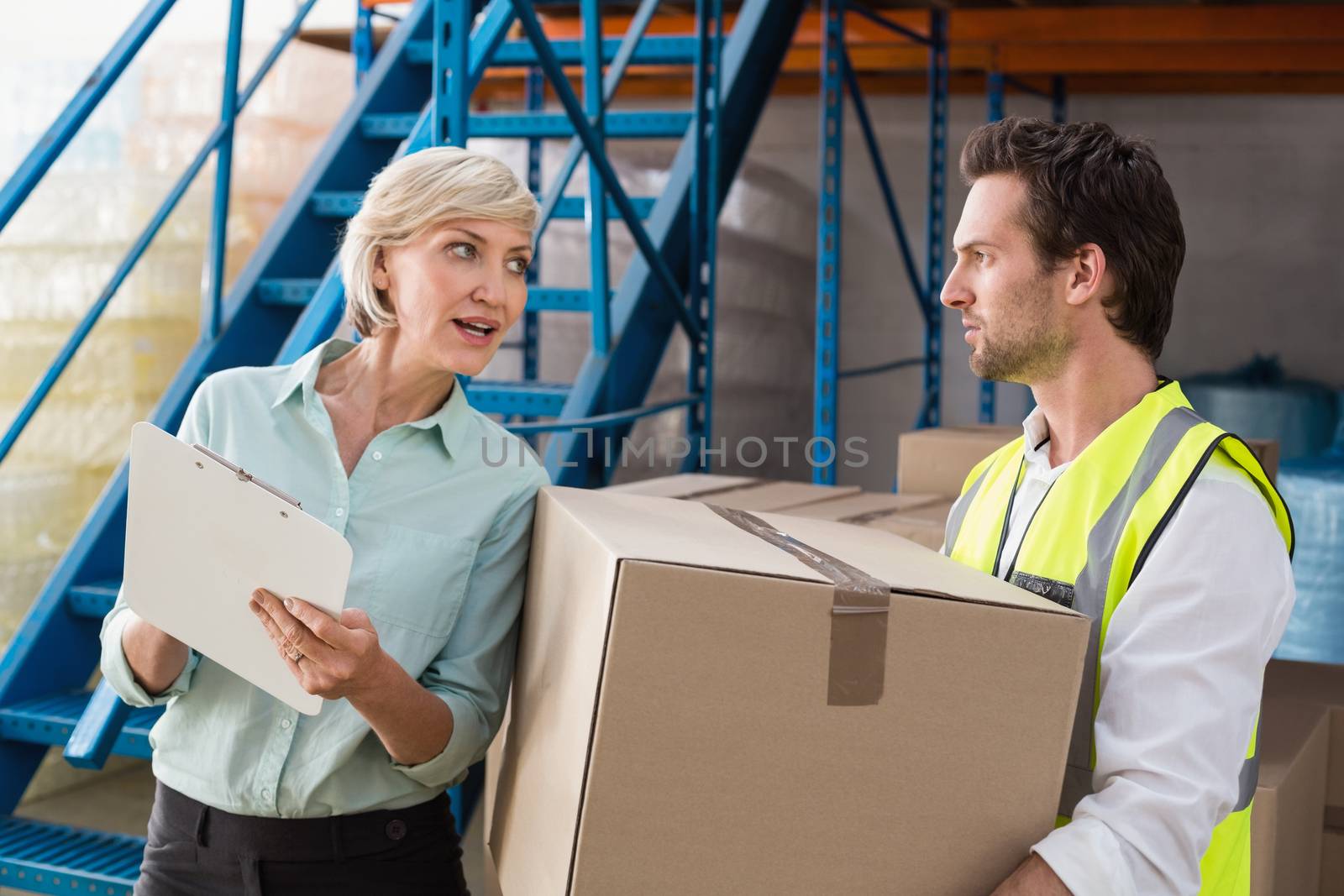 Warehouse manager and worker talking together in a large warehouse