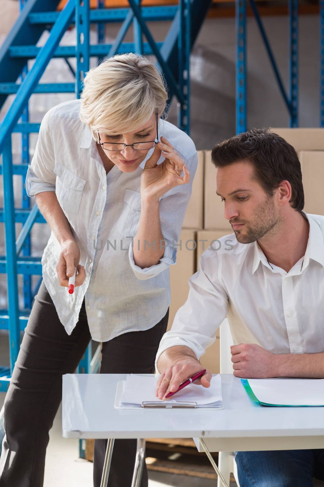 Focused warehouse team working together with clipboard in a large warehouse