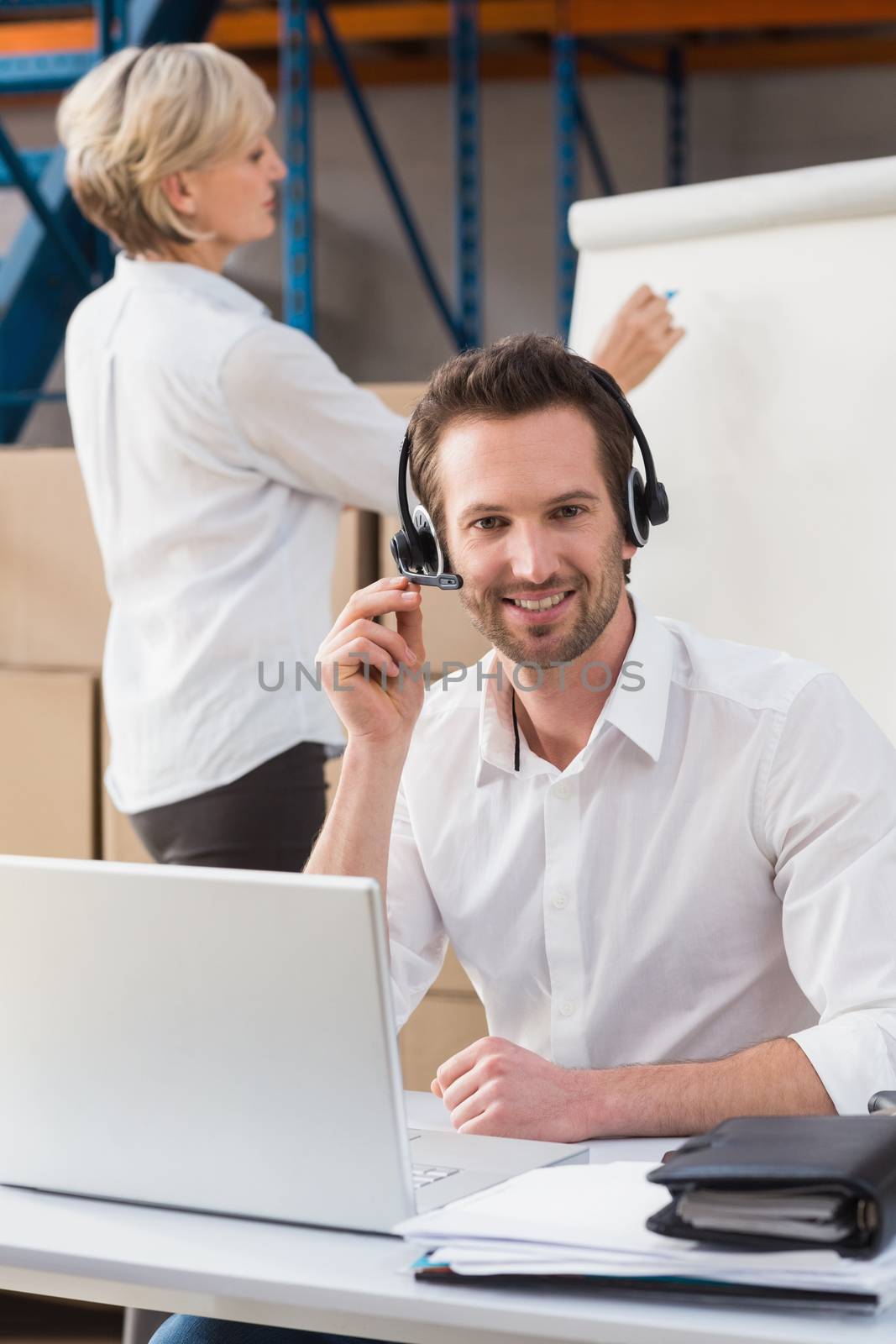 Warehouse manager using laptop during a presentation in a large warehouse