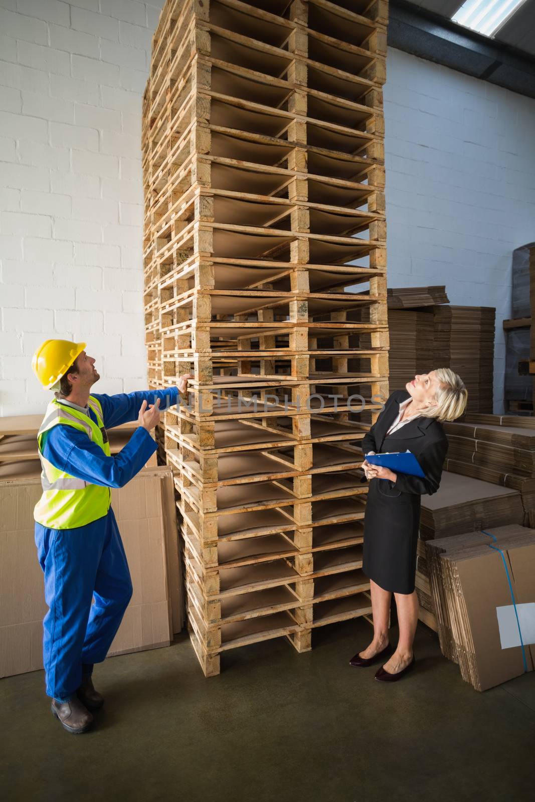 Warehouse worker and his manager looking stack of pallet in a large warehouse