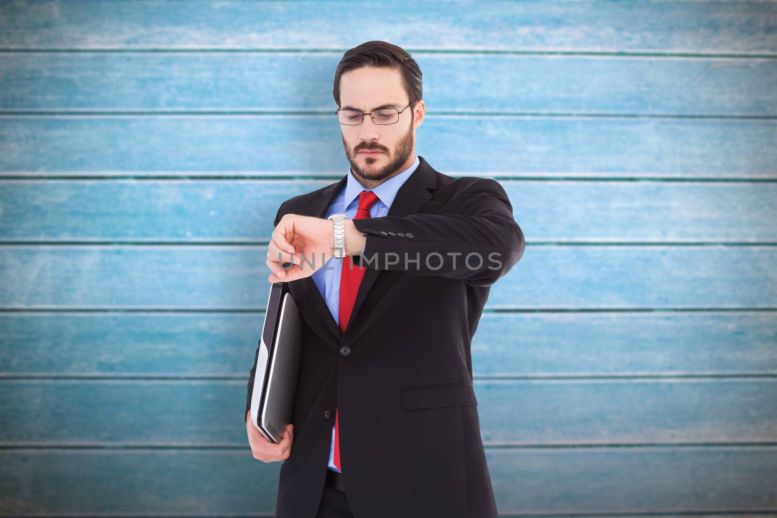 Frowning young businessman checking time against wooden planks