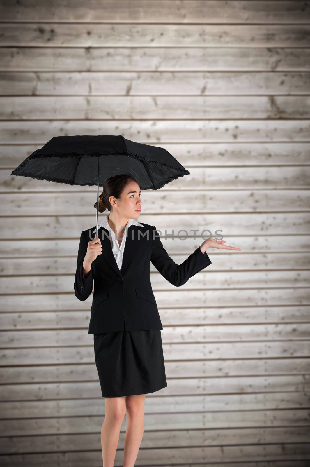 Composite image of young businesswoman holding umbrella by Wavebreakmedia