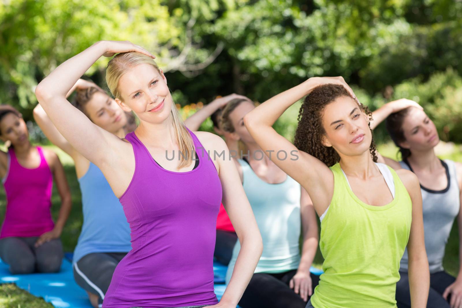 Fitness group doing yoga in park on a sunny day
