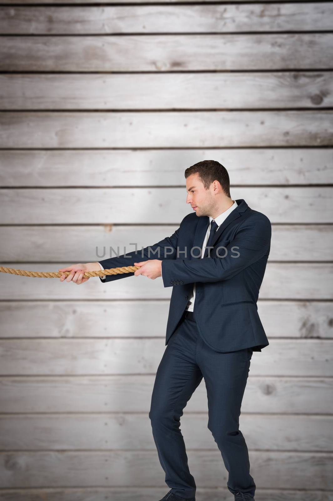 Composite image of young businessman pulling a rope by Wavebreakmedia