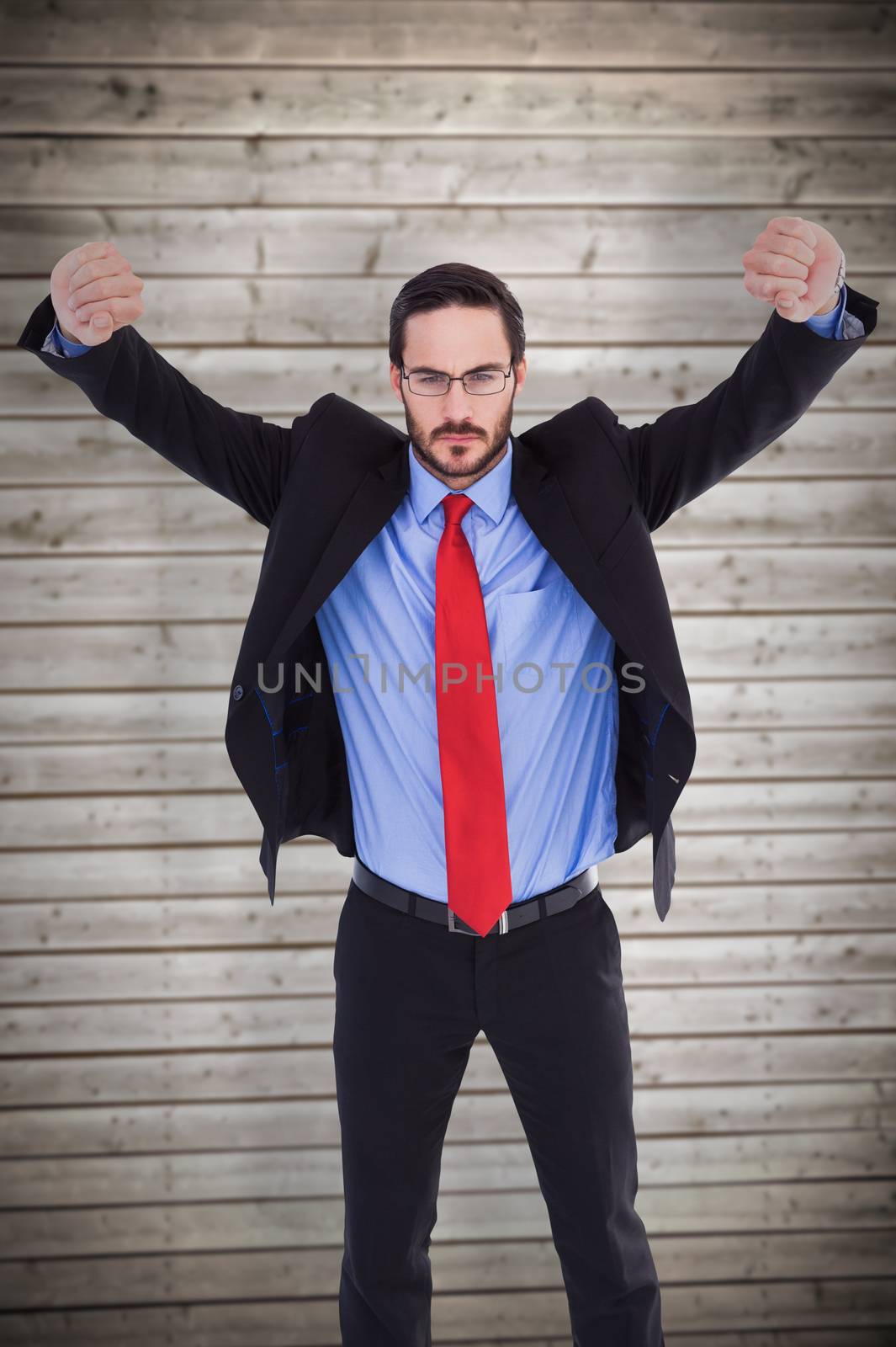 Unsmiling businessman standing with arms raised against wooden planks background