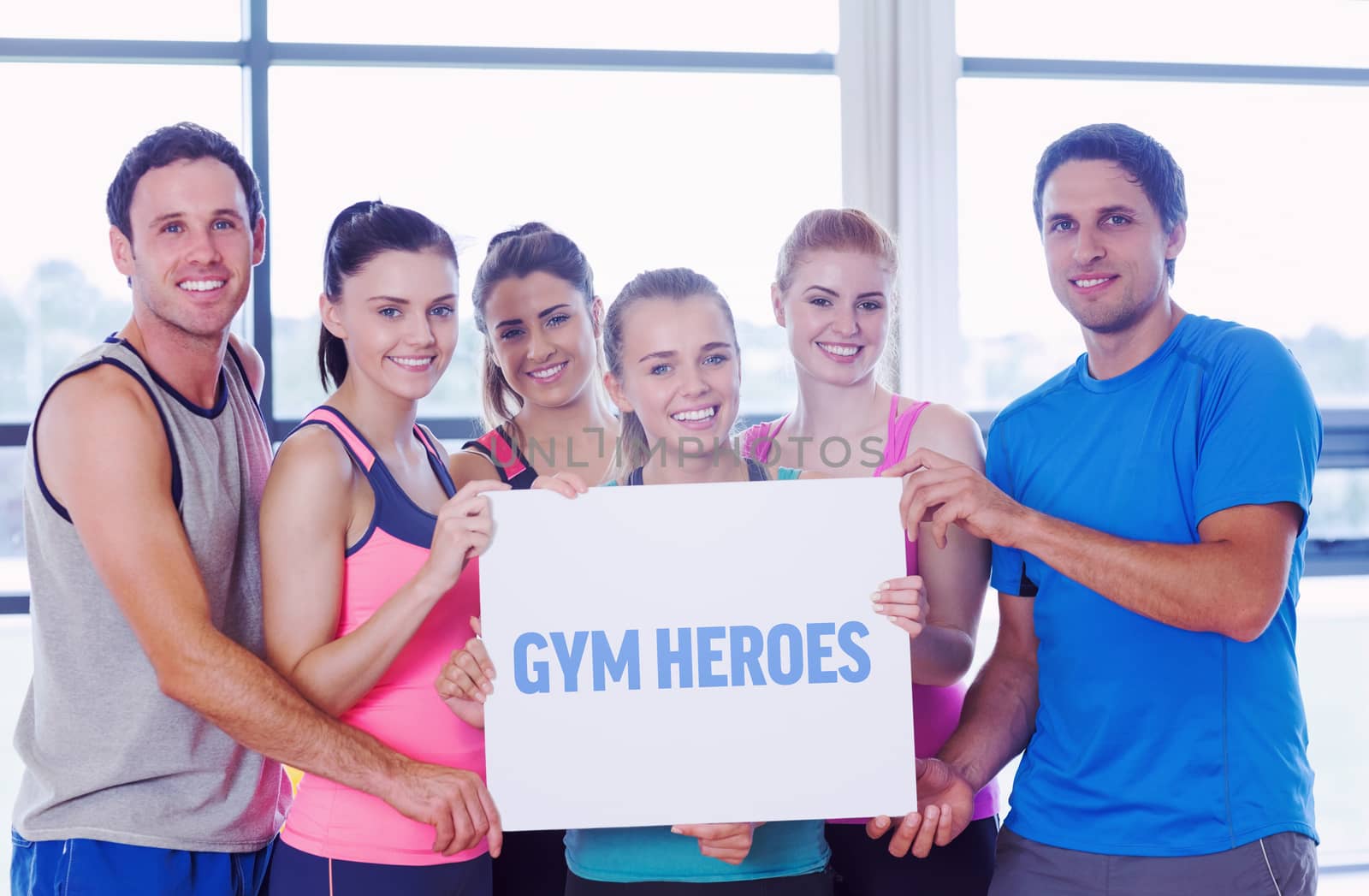 The word gym heroes against portrait of a group of fitness class holding blank paper