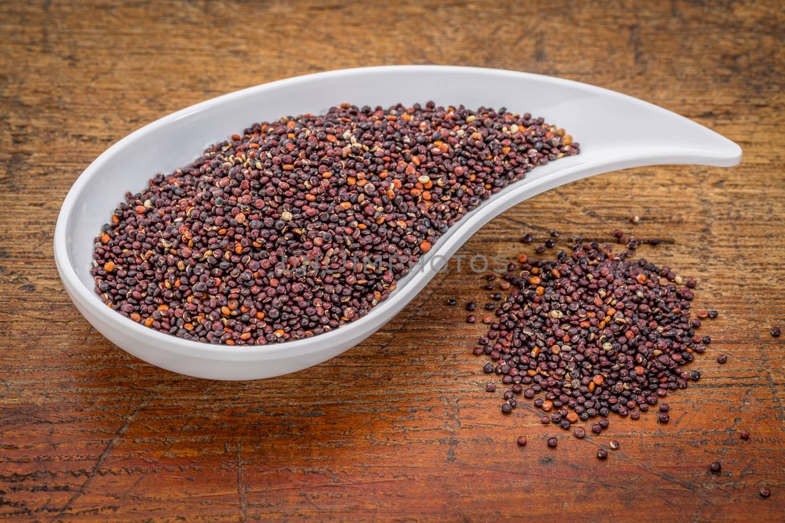 gluten free black quinoa grain grown iin Bolivia ,  a teardrop shaped bowl against rustic grunge wood