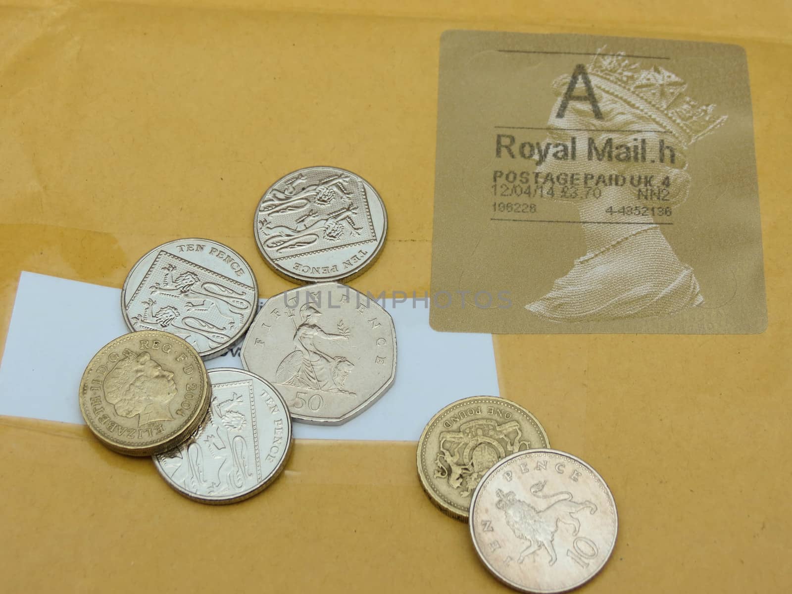 LONDON, CIRCA APRIL 2014: British Pounds coins (currency of United Kingdom) over a mail envelope with British stamp, useful a trip to the UK concept