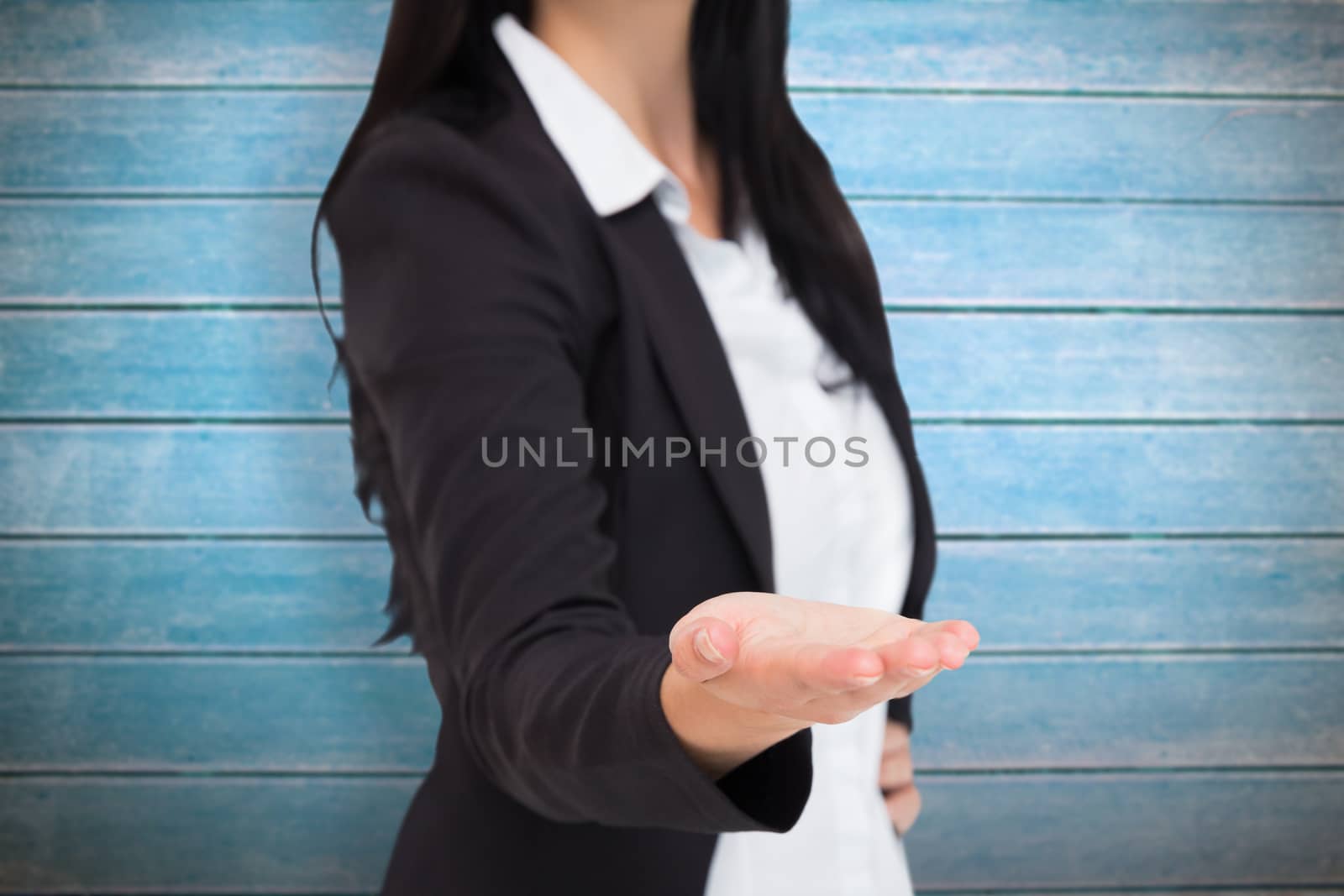 Pretty businesswoman presenting with hand against wooden planks