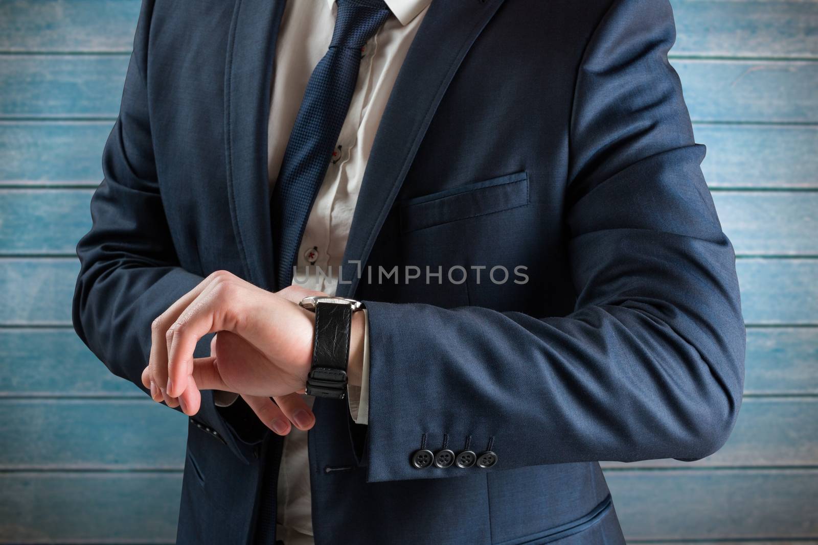 Businessman checking the time on watch against wooden planks