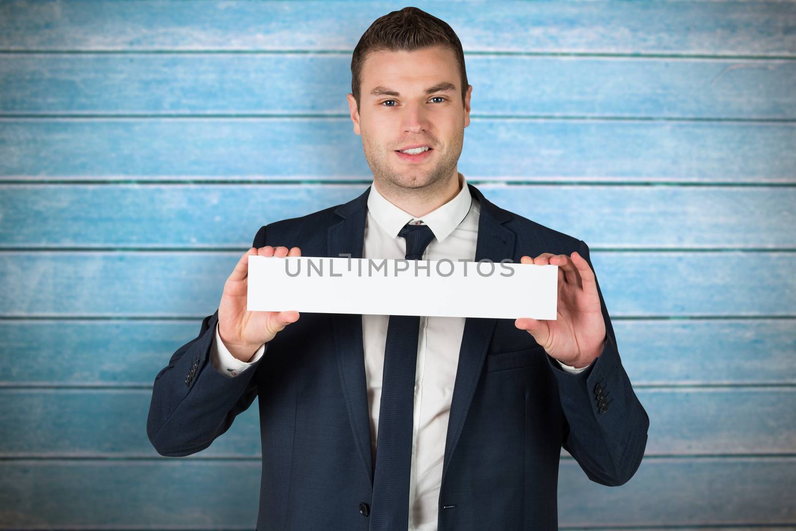Happy businessman showing card to camera against wooden planks