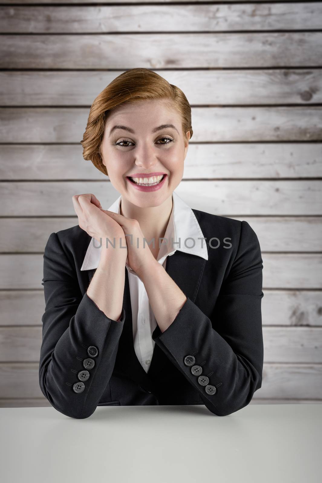 Composite image of excited redhead businesswoman sitting at desk by Wavebreakmedia