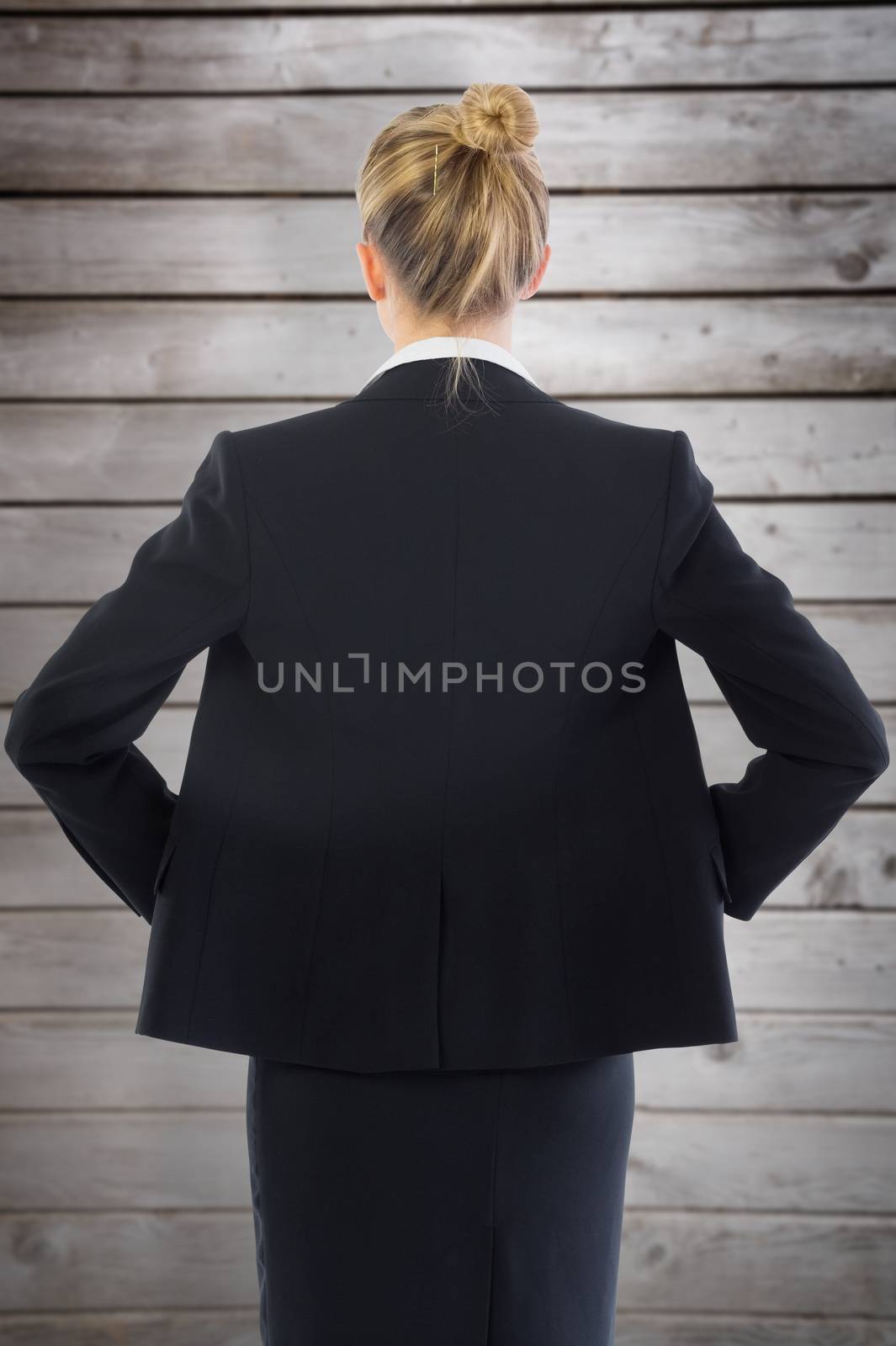 Businesswoman standing with hands on hips against wooden planks