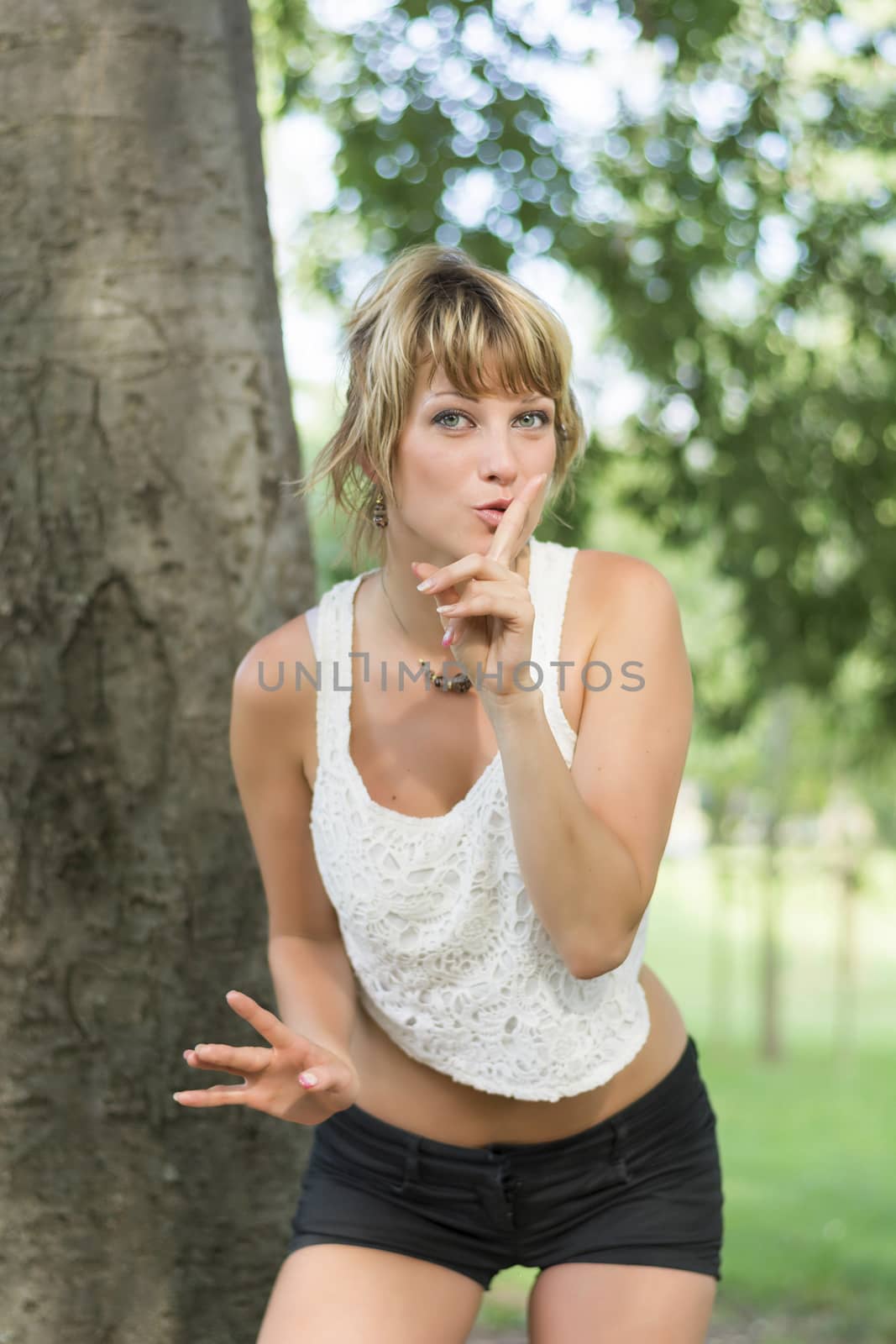 Pretty young woman making a shushing gesture by artofphoto