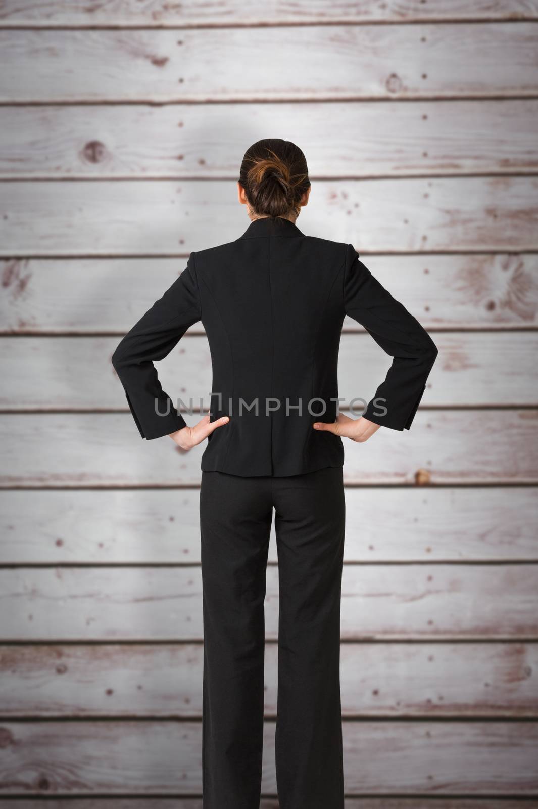 Composite image of businesswoman standing with hands on hips by Wavebreakmedia