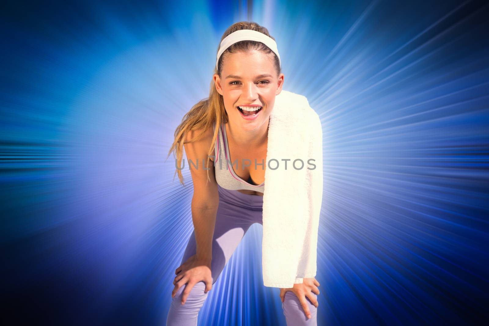 Sporty smiling blonde standing on the beach with towel against abstract background