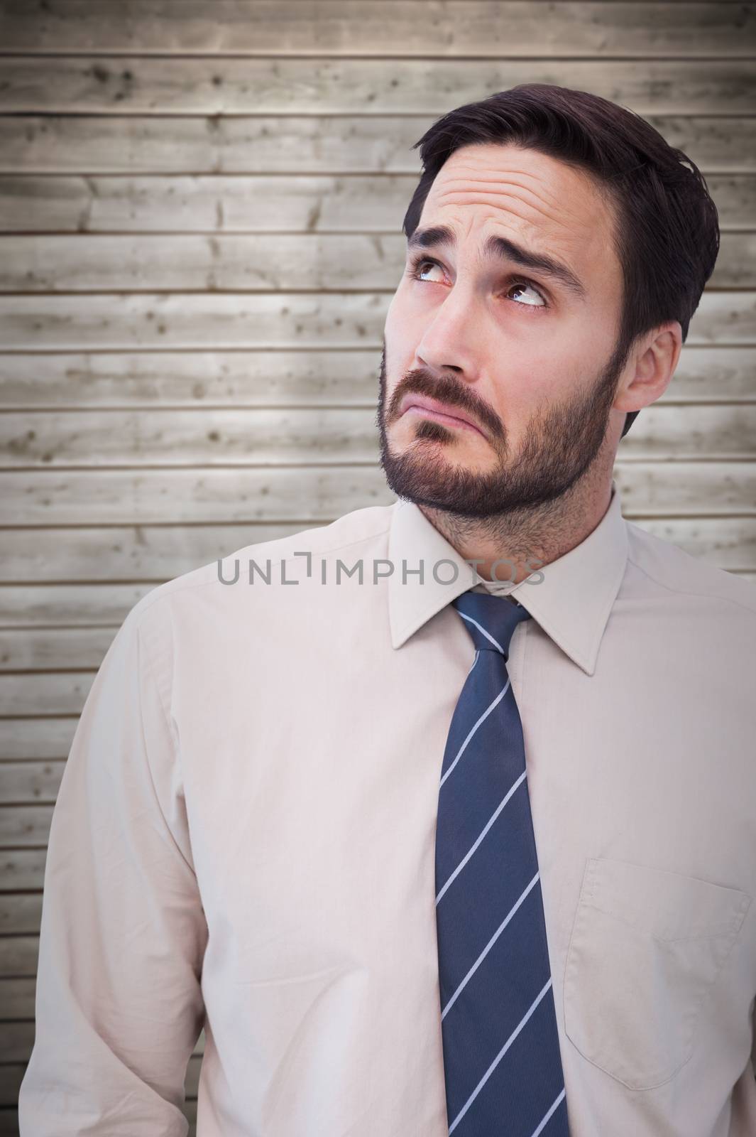 Portrait of a nervous businessman looking up against wooden planks background
