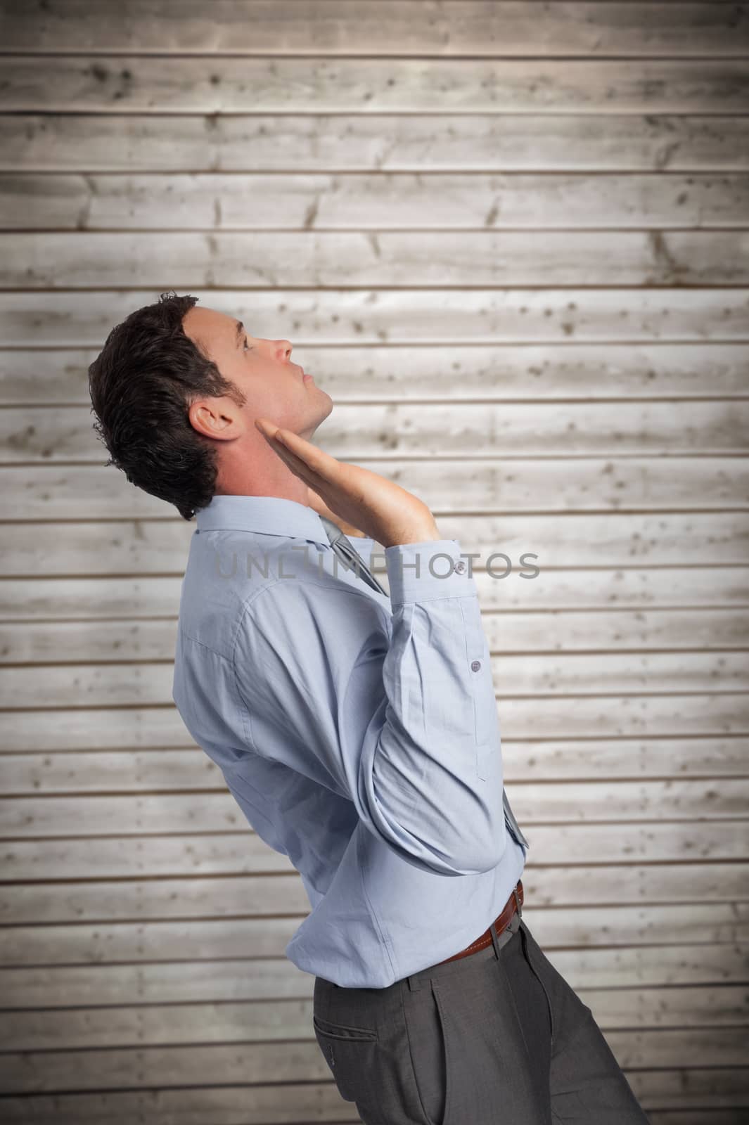 Businessman standing with arms pushing up against wooden planks background