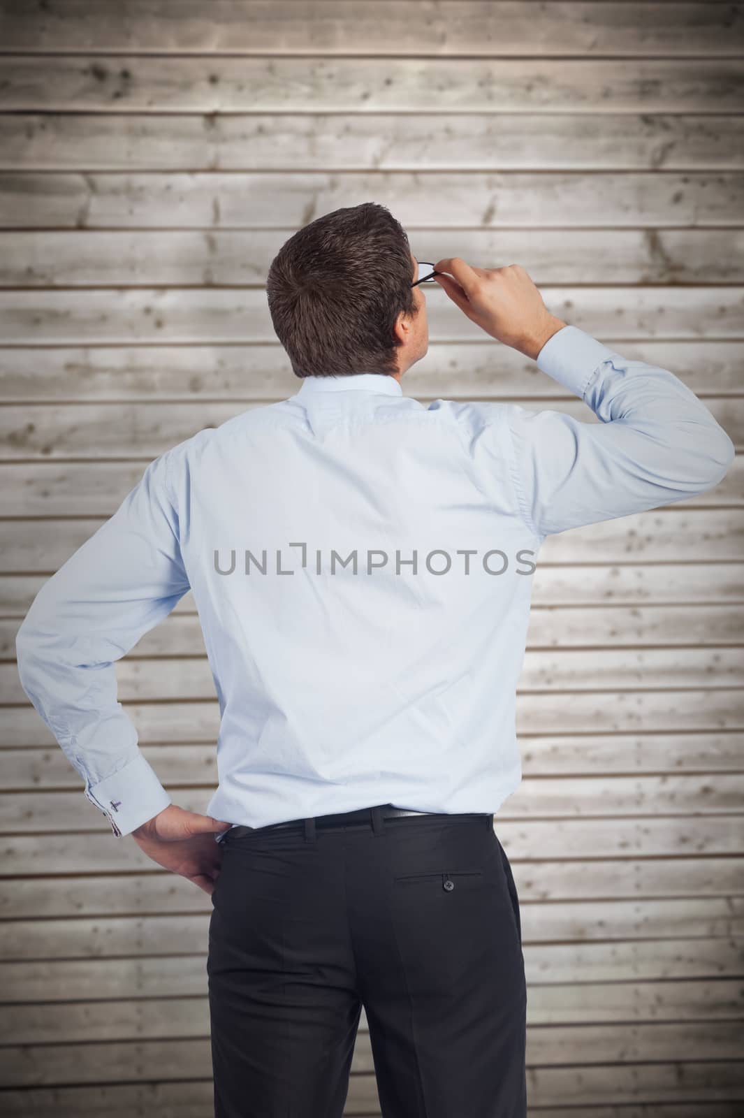 Thinking businessman tilting glasses against wooden planks background