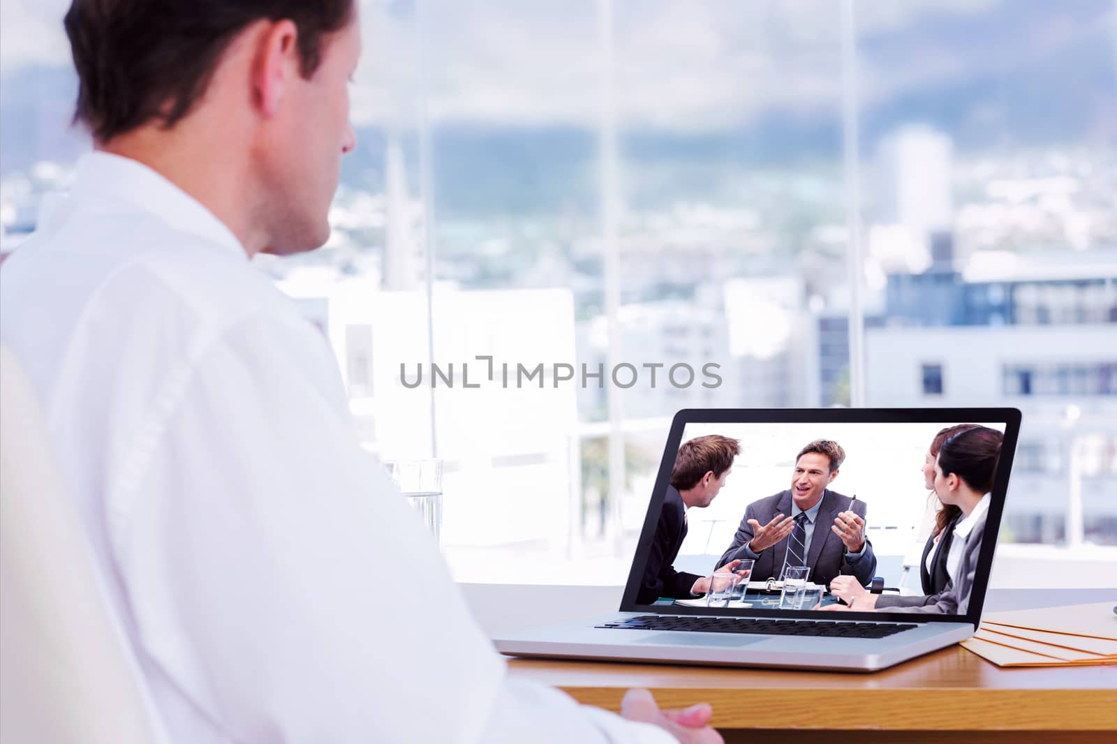 Businessman looking at a laptop against charismatic chairman talking with his team 