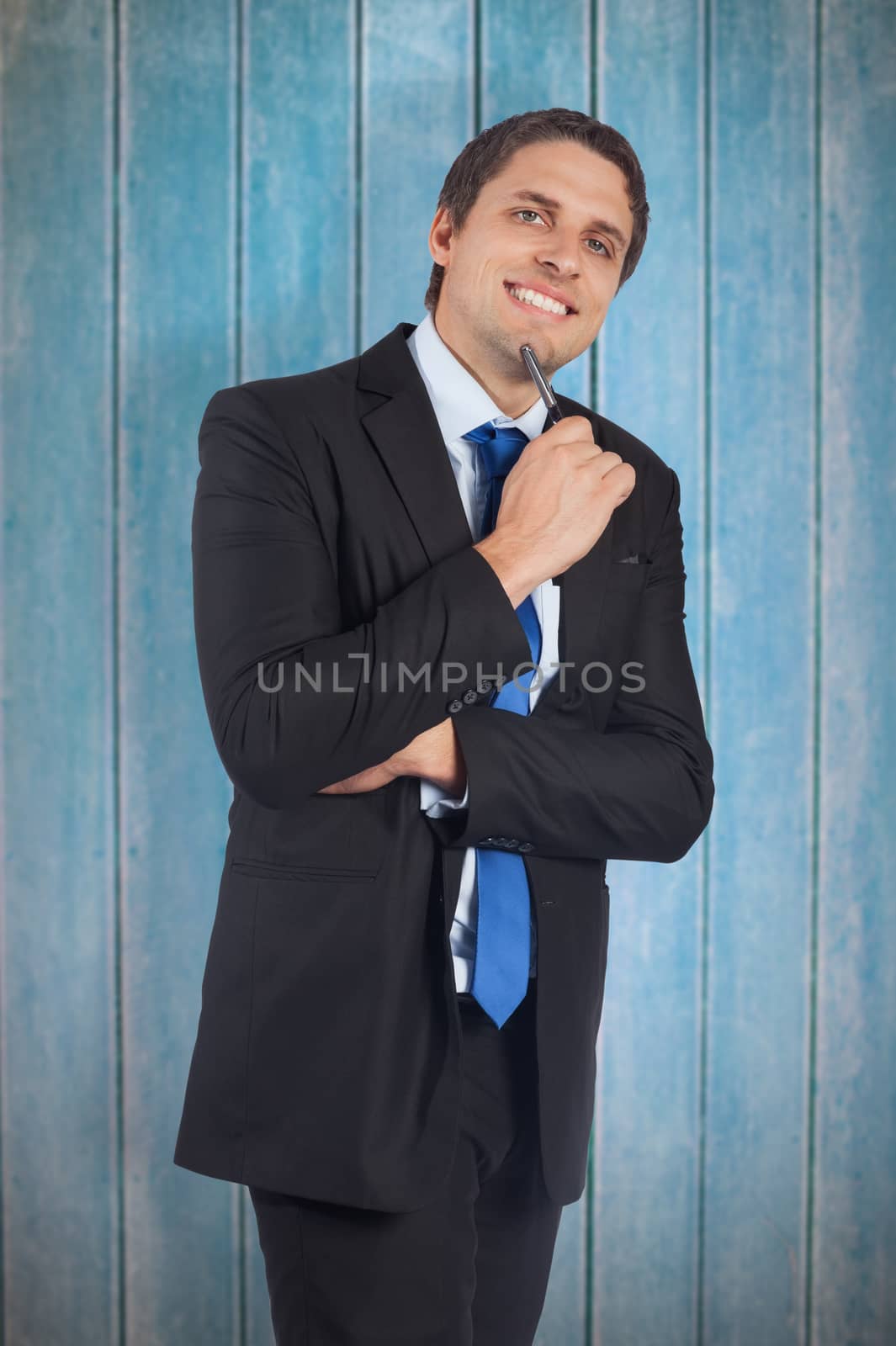 Thinking businessman holding pen against wooden planks