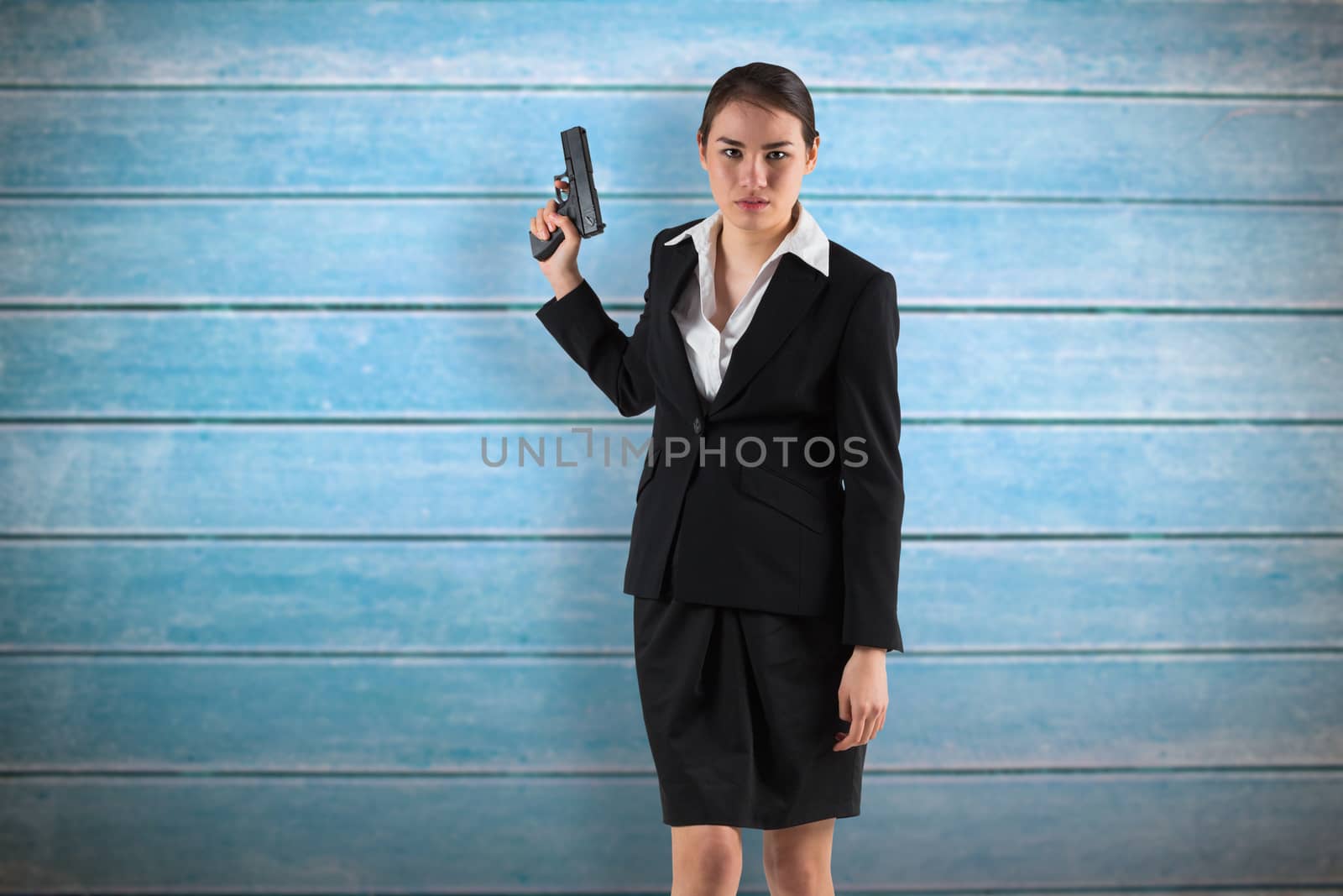 Businesswoman holding a gun against wooden planks