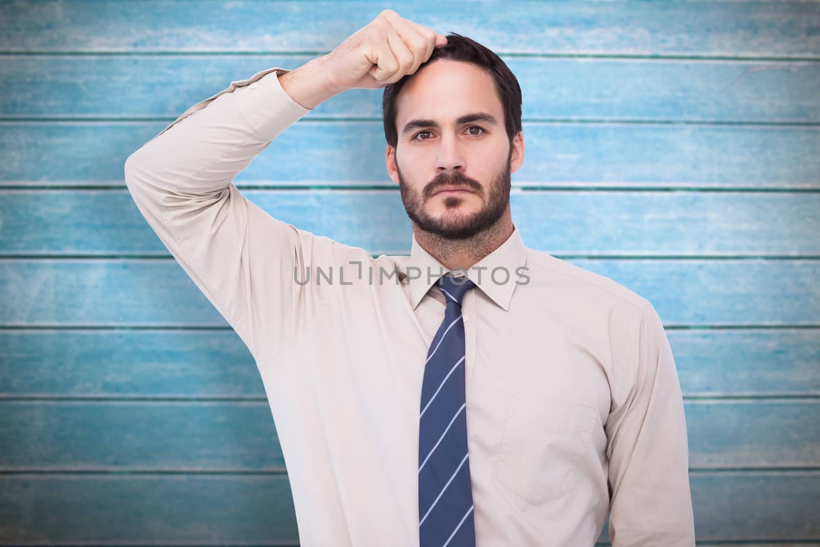 Serious businessman standing with hand on head against wooden planks