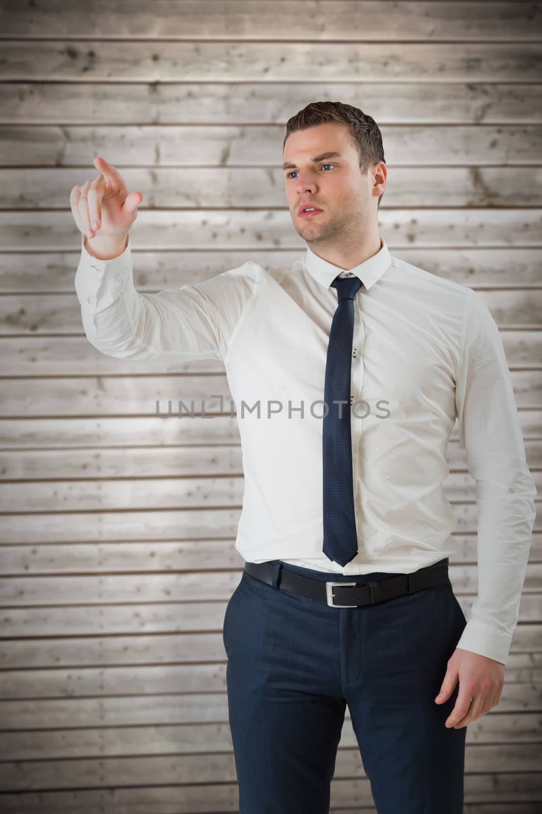 Composite image of young serious businessman pointing  by Wavebreakmedia