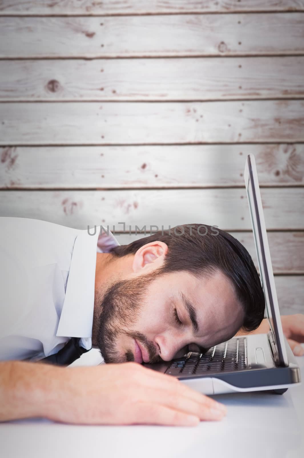 Composite image of businessman resting head on laptop keyboard by Wavebreakmedia