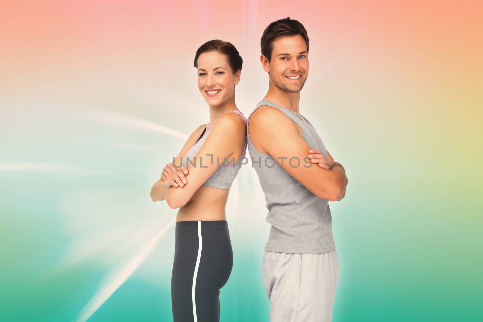 Portrait of a happy fit young couple with hands crossed against abstract background
