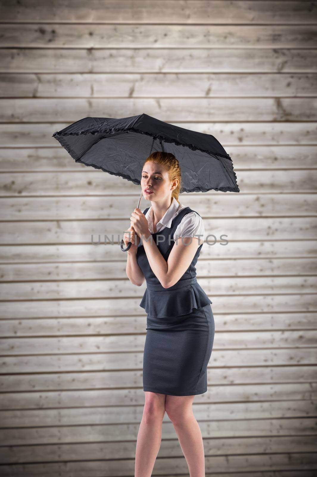 Composite image of pretty redhead businesswoman holding umbrella by Wavebreakmedia
