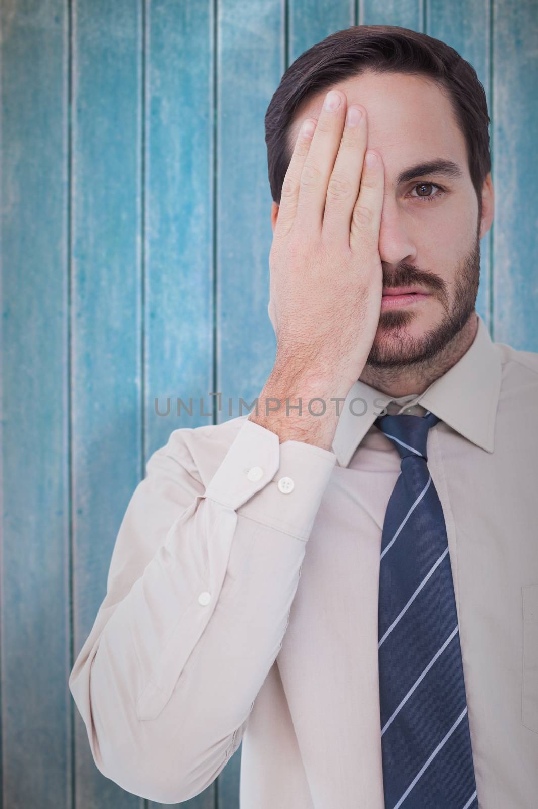 Unsmiling patient looking at camera with one eye  against wooden planks