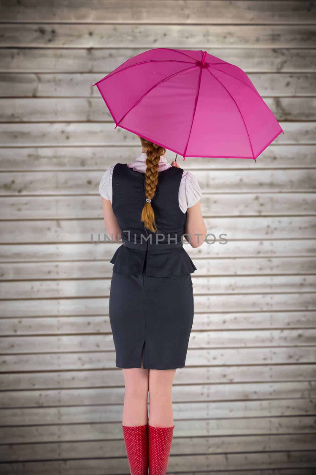 Pretty redhead businesswoman holding umbrella against wooden planks background