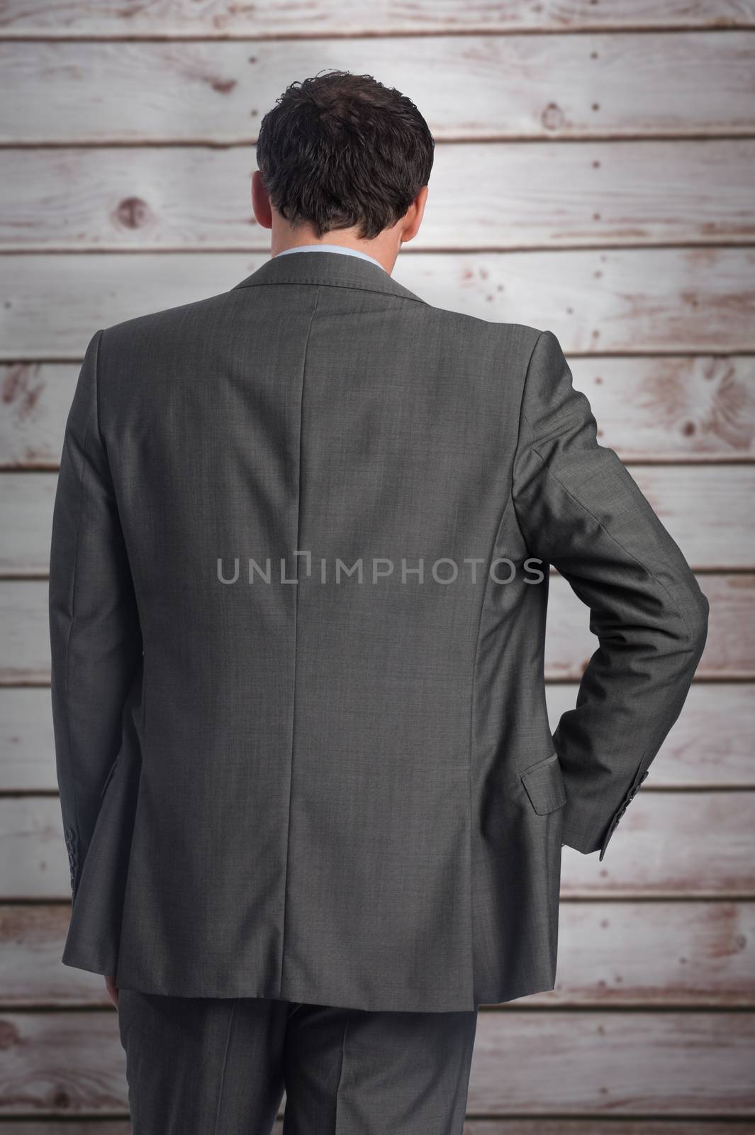 Composite image of businessman with hand on hip by Wavebreakmedia