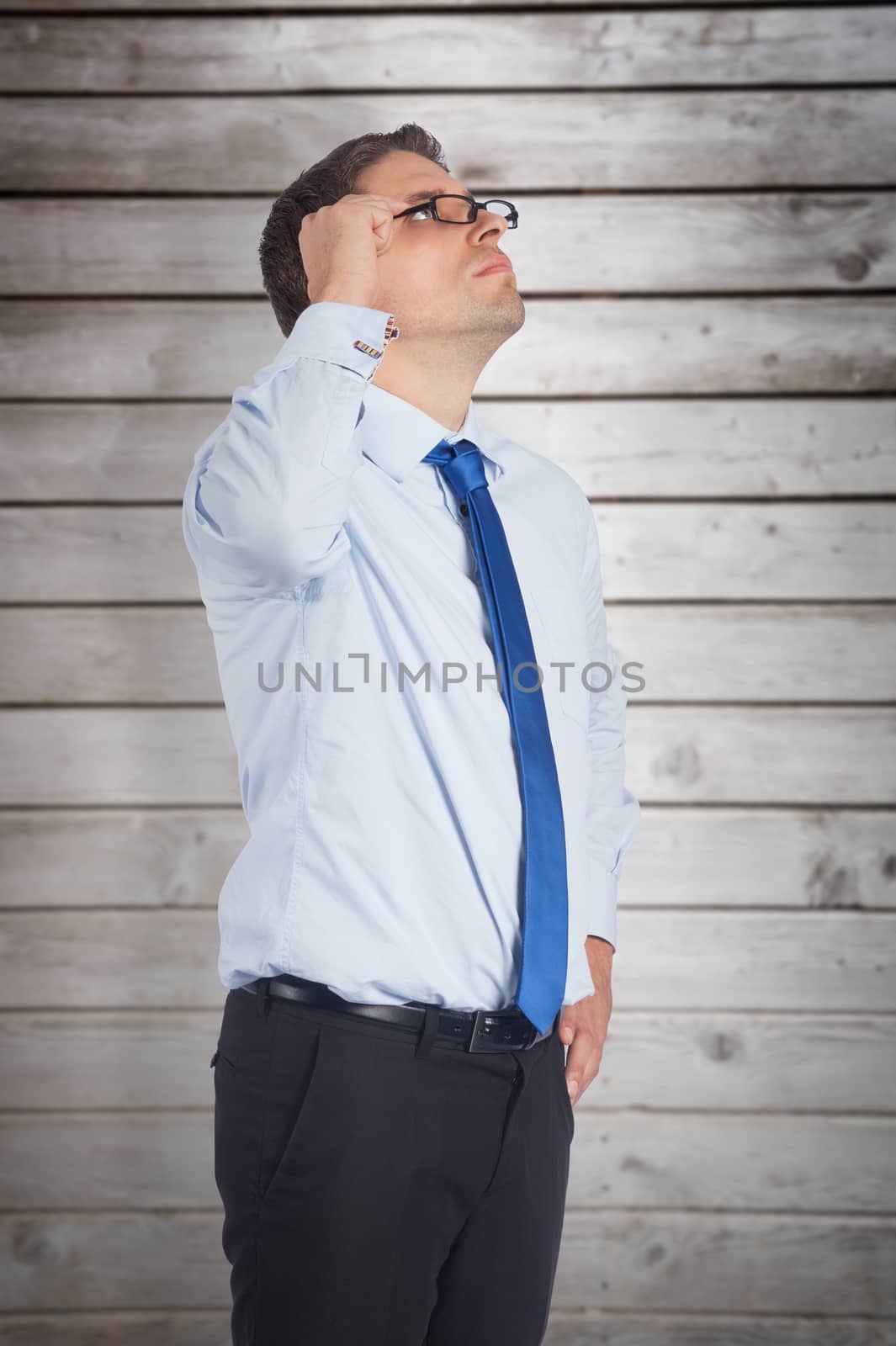 Thinking businessman tilting glasses against wooden planks