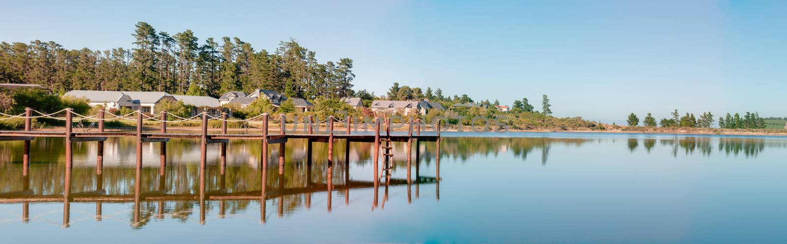 CAPE TOWN, SOUTH AFRICA - DECEMBER 18, 2014: Early morning panorama of houses next to a dam with jetty on the Wedderville Estate near Sir Lowrys Pass