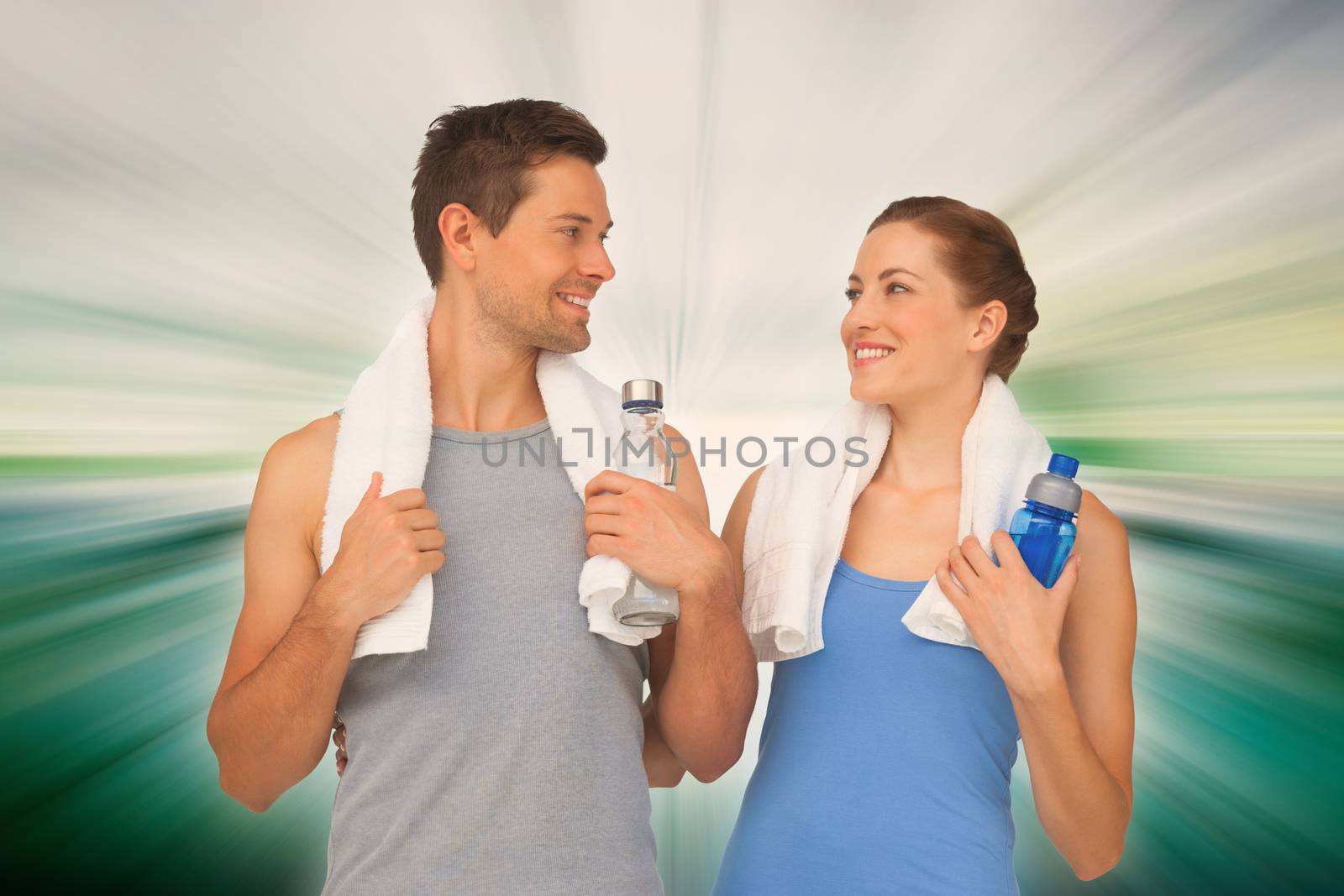 Happy fit young couple with water bottles against abstract background