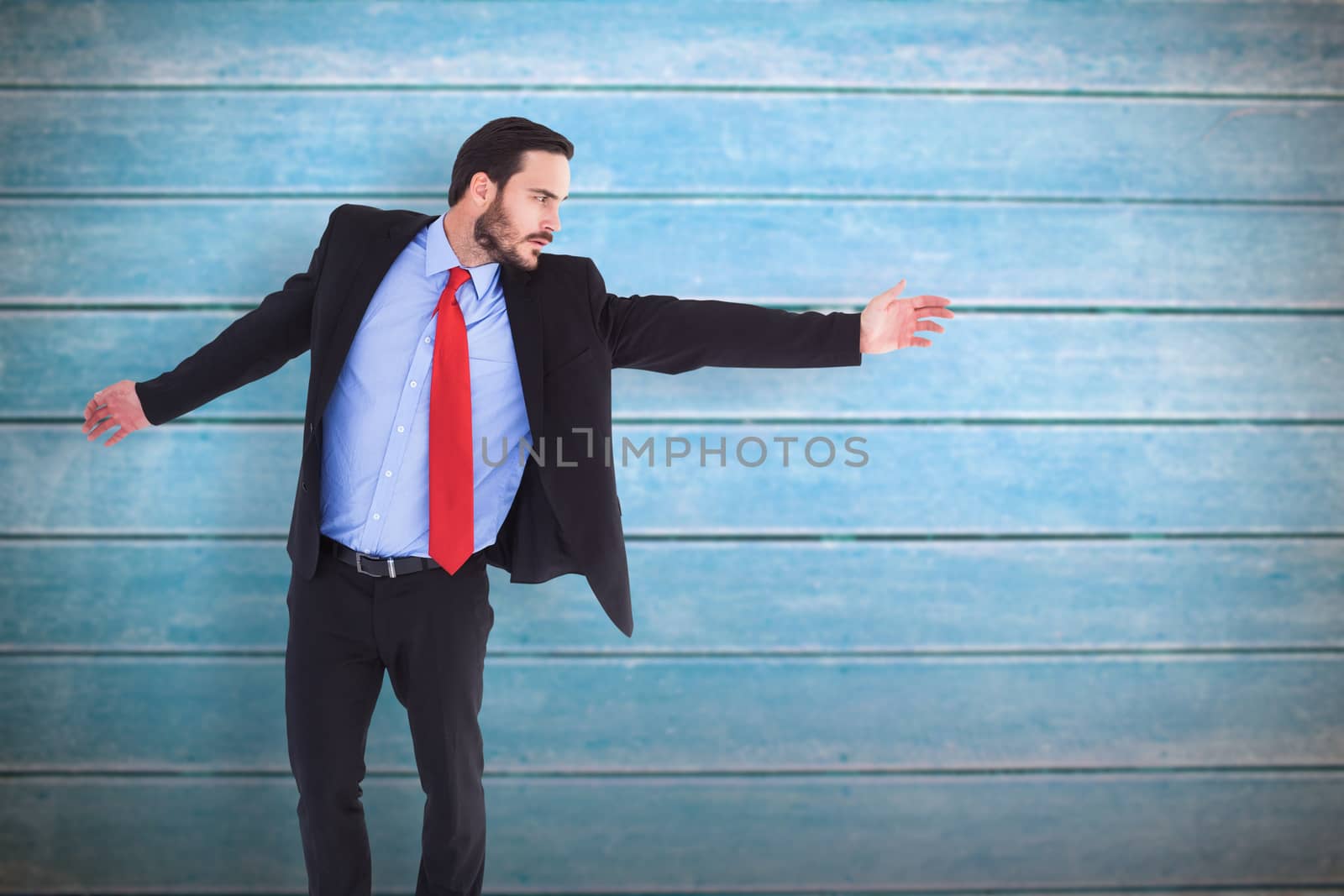 Serious businessman in suit gesturing with hand against wooden planks