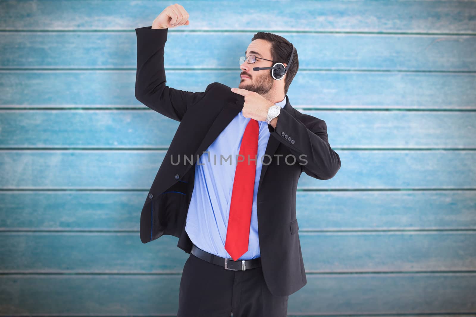 Smiling man wearing a headset while pointing his bicep against wooden planks