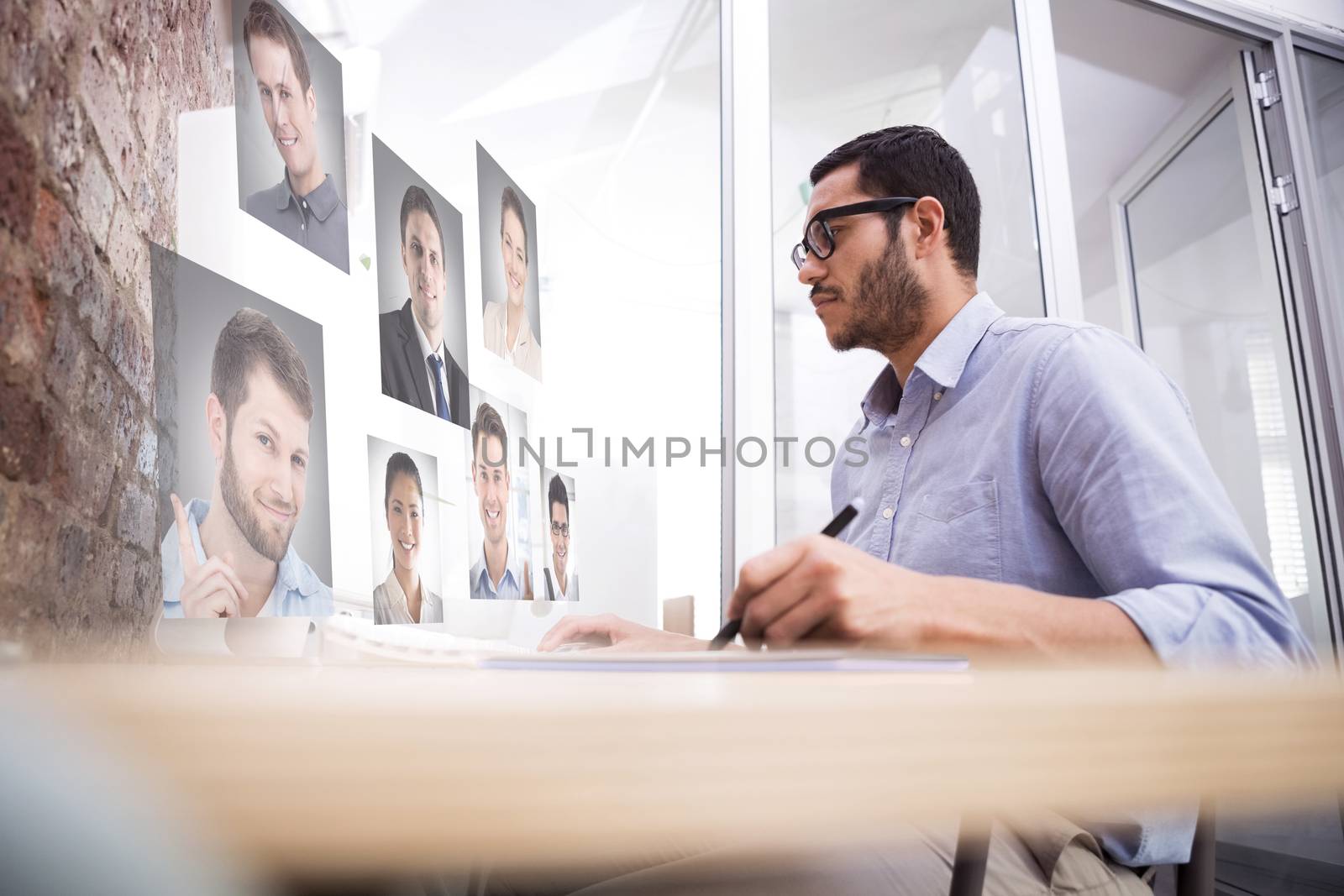 Man working at desk with computer and digitizer against profile pictures