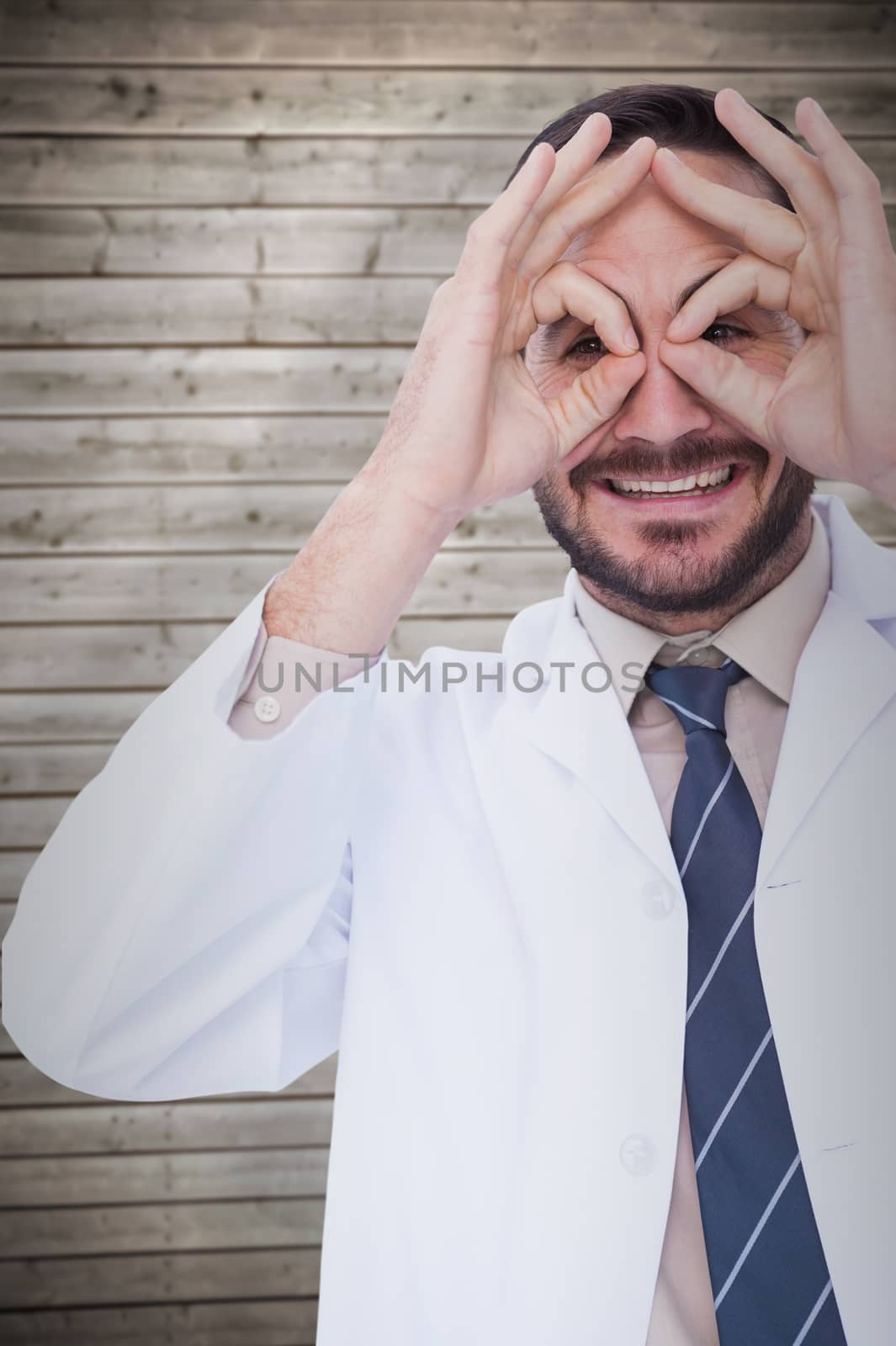 Smiling doctor forming eyeglasses with his hands against wooden planks background