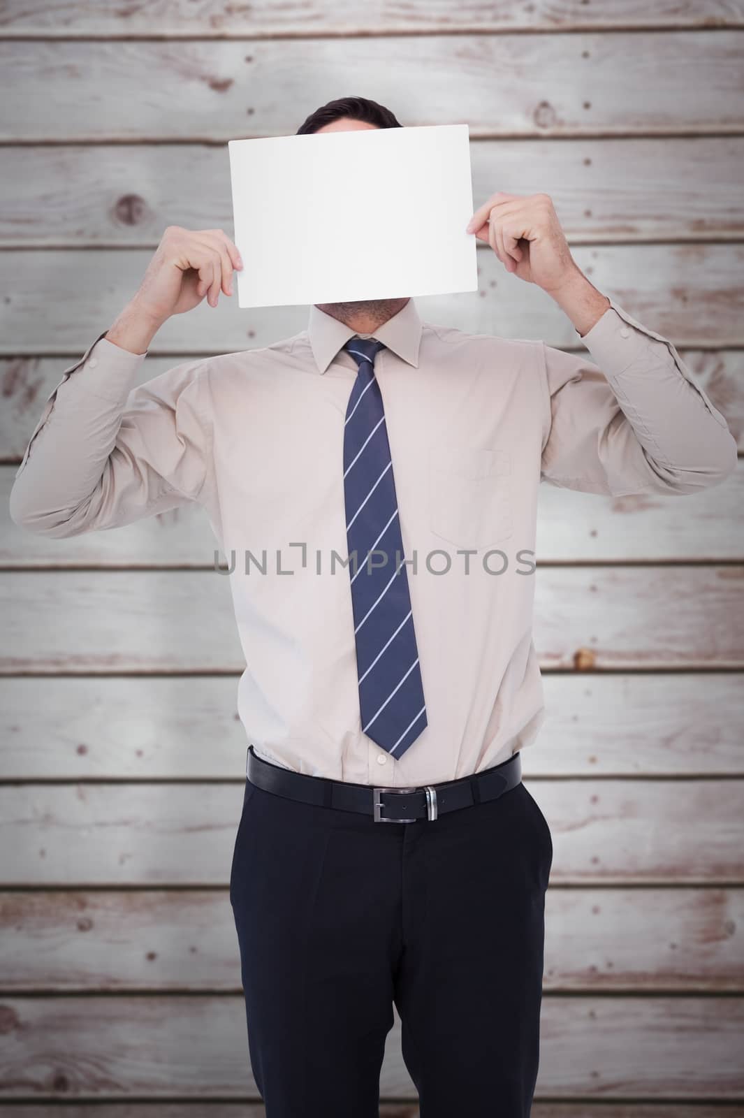 Businessman showing card in front of his head against wooden planks