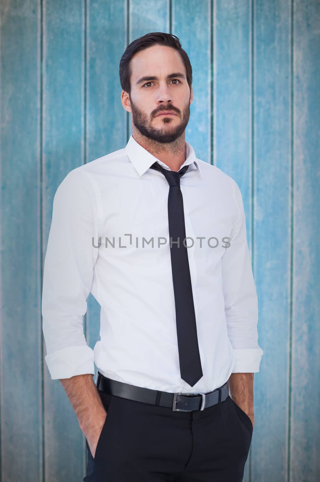 Unsmiling businessman standing with hands in pockets against wooden planks