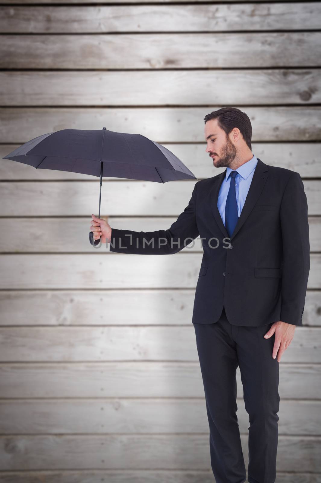 Composite image of businesswoman in suit holding umbrella by Wavebreakmedia