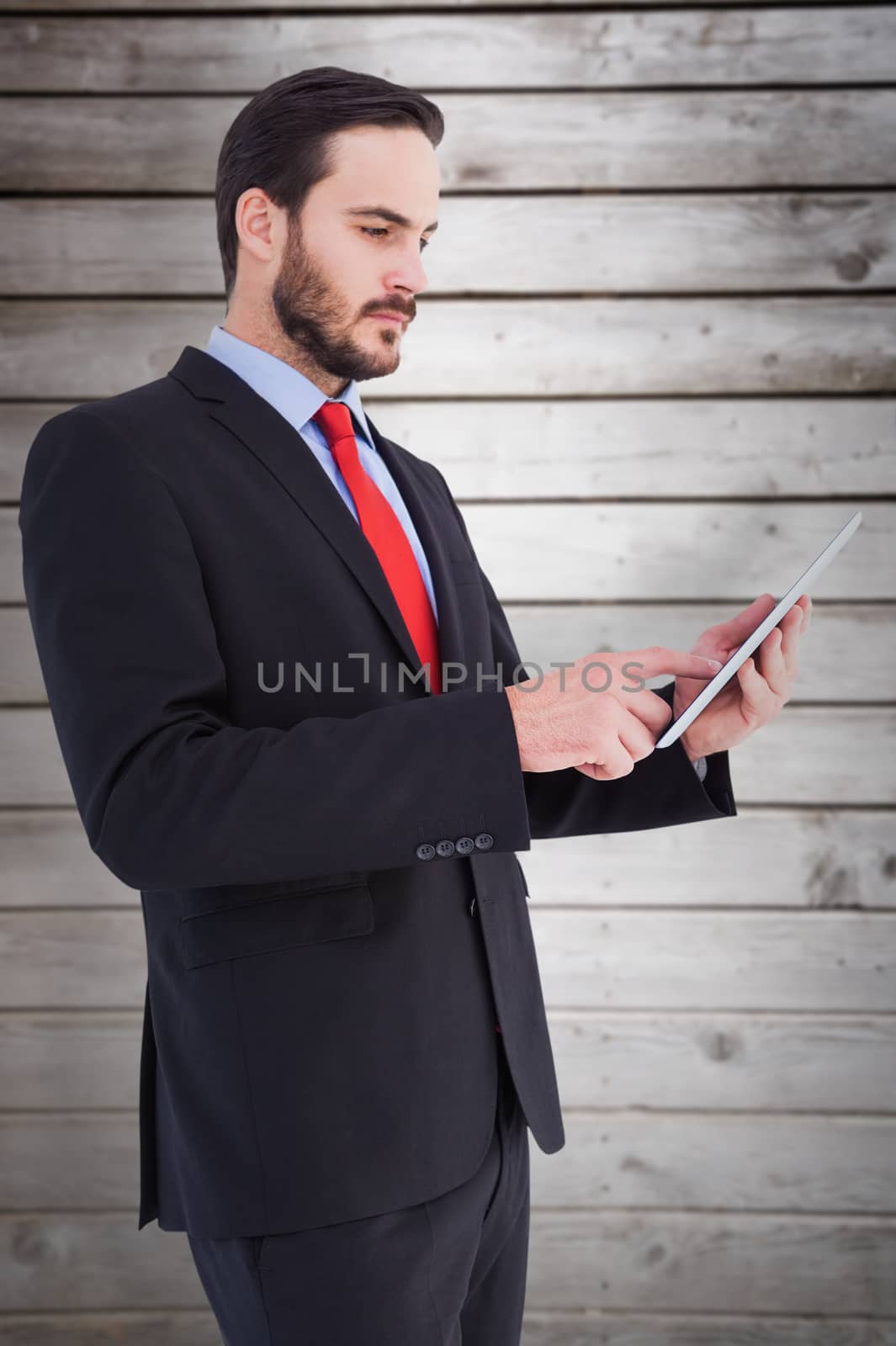 Businessman scrolling on his digital tablet against wooden planks