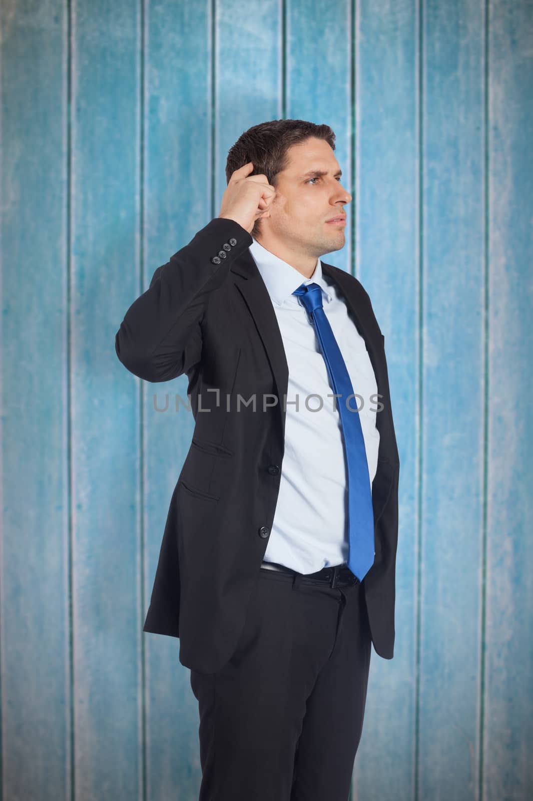 Thinking businessman scratching head against wooden planks