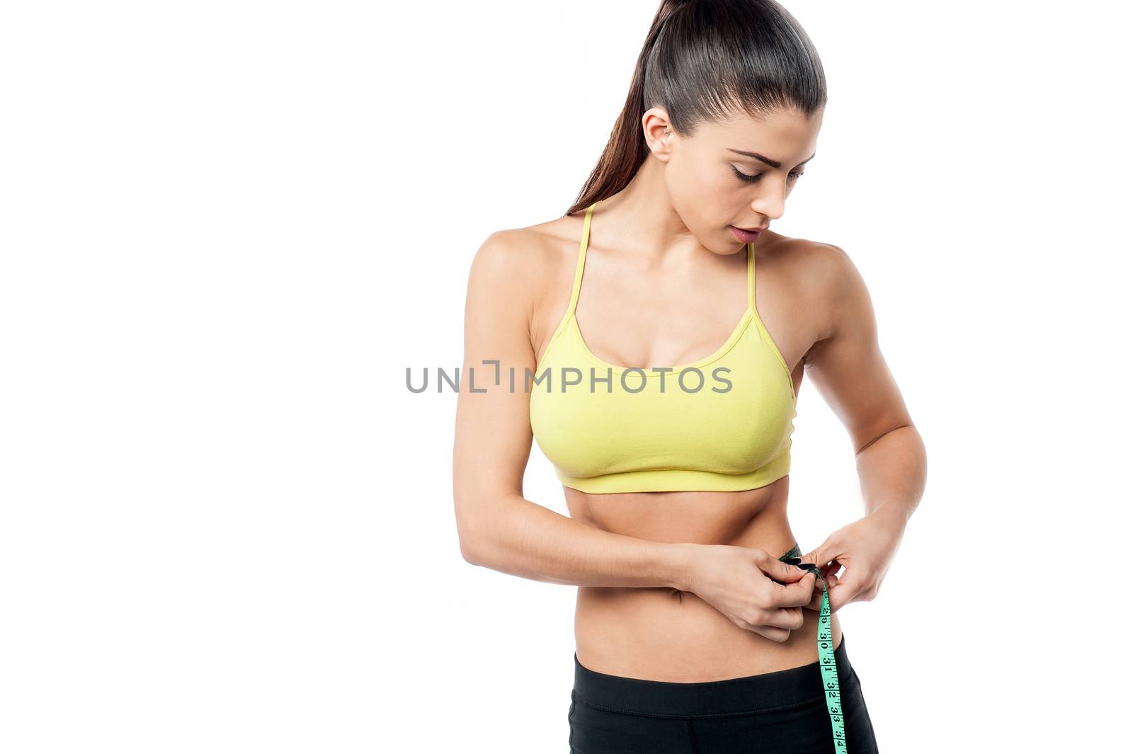 Fit woman measuring her waist with tape