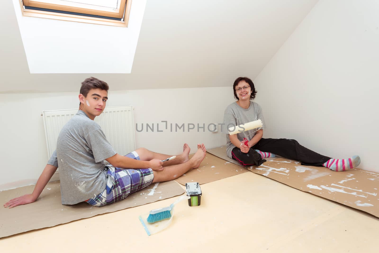 housewife with son resting after painting wall to white at home