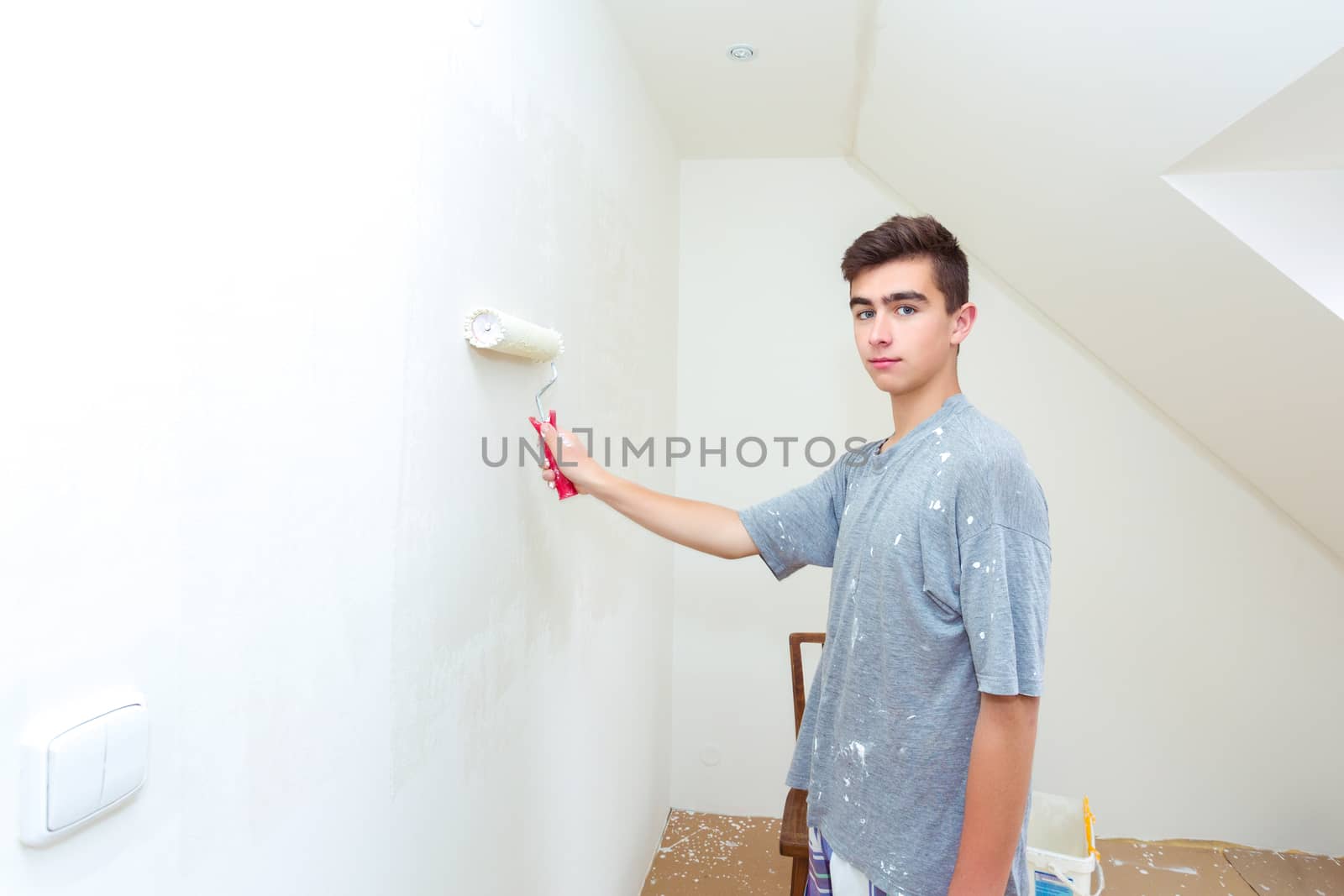 happy young teenager painting wall to white at home