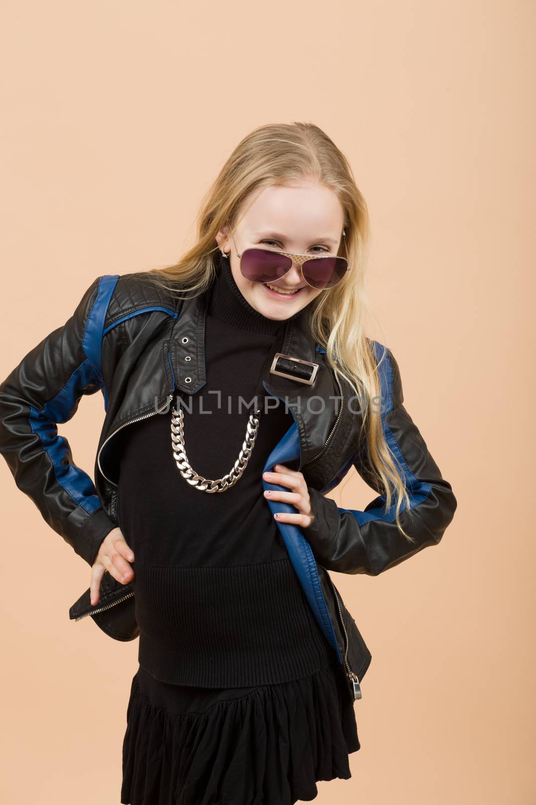 Portrait of fashion smiling european little long hair blonde girl posing in atelier with sunglasses